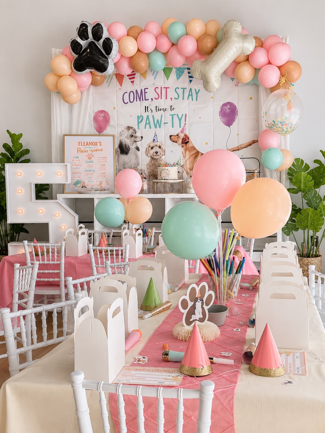 A pastel puppy-themed birthday party setup with balloon garland and favor boxes at Pikopye's Town